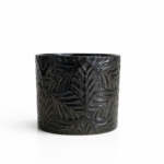 Glossy black ceramic planter with raised tropical leaf pattern against a white background.