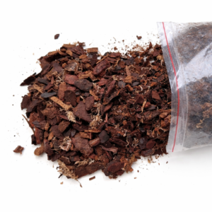 Orchid potting mix made of bark, buffered coco chunks and sphagnum moss spilling from a clear bag onto a white background.