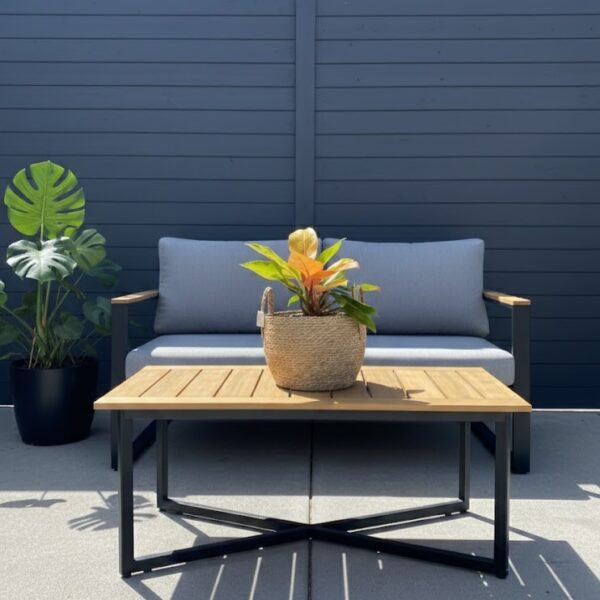 Large round natural seagrass woven basket with upright handles and orange plant in on coffee table in modern outdoor seating area